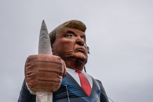 Eine aufblasbare Trump Figur, die eine KuKluxKlan Kappuze hält